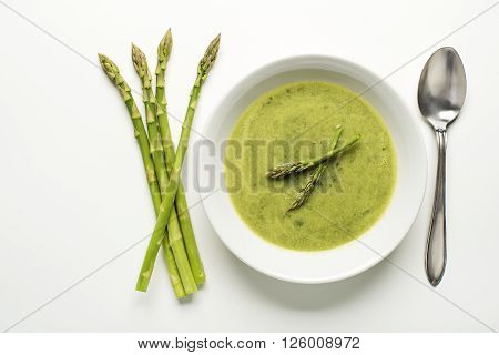 Fresh asparagus soup on white background overhead shoot