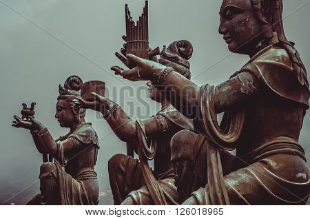 Buddhist statues praising and making offerings to the Tian Tan Buddha. The Po Lin Monastery and the Lantau Peak in the background, in Hong Kong. Hong Kong is popular tourist destination of Asia.