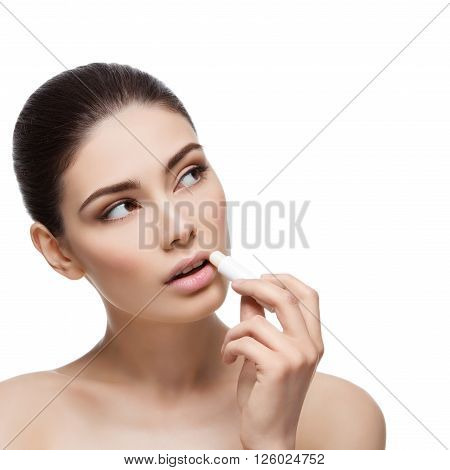 Beautiful young woman applying chapstick to lips. Isolated over white background. Copy space. Square composition.