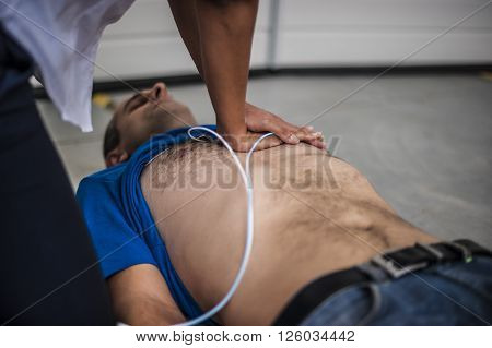 rescuer assisting an unconscious man with cardiac compression chest and defibrillation