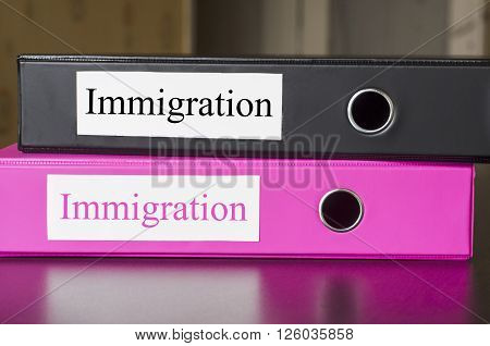 Bright office folders over dark background and immigrations text concept