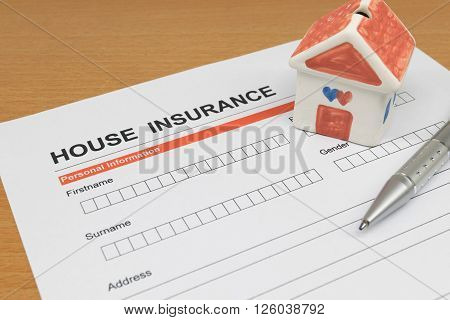House Insurance application form with model house and pen