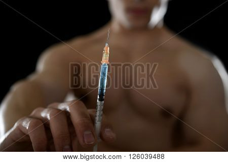young body building sportsman using steroids for increasing sport and athletic performance holding close up syringe isolated on back background in sport cheat doping and illegal use of hormones