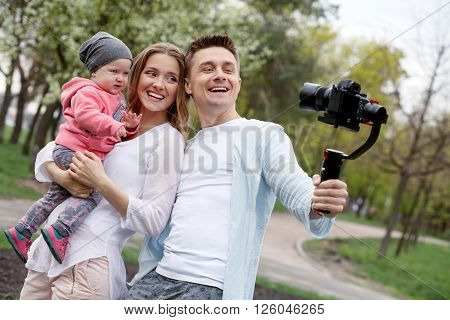 Happy young family taking selfies with her camera on the gimbal steadycam