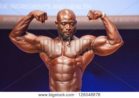 MAASTRICHT THE NETHERLANDS - OCTOBER 25 2015: Male bodybuilder Elias Bogane flexes his muscles and shows his best physique in a front double biceps pose on stage at the World Grandprix Bodybuilding and Fitness of the WBBF-WFF
