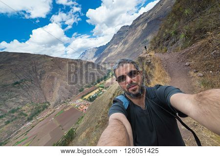 Fellow traveler taking selfie while visiting Inca site of Pisac Sacred Valley major travel destination in Cusco region Peru. Expansive view.