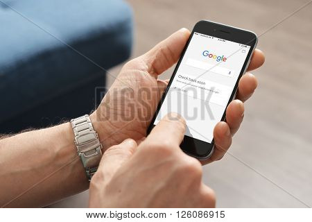 Kiev Ukraine - March 06 2016: A man touches on screen new Apple iPhone 6 smartphone device to open google application.