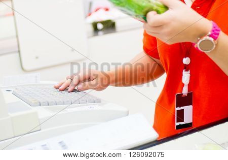 Counter cashier key price of farm product for customer at supermarket.