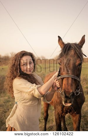 Beautiful girl with a horse outdoors in the countryside.