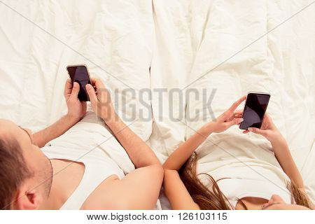 Top View Of Young Couple Lyng In Bed With Mobile Phones