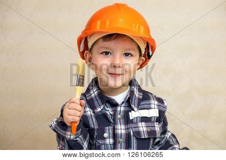 Little boy in the construction helmet with a brush.