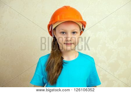 Little girl builder in a helmet and with a brush.