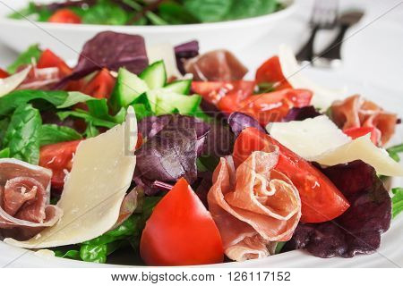 Fresh Mediterranean salad with prosciutto, parmesan cheese and vegetables.