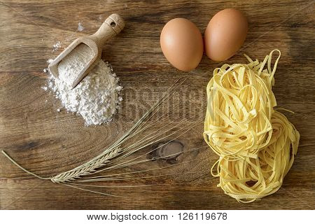noodles, eggs, flour and wheat on wood