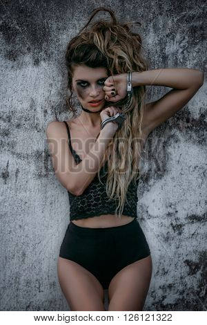 Worried woman with handcuffs against wall