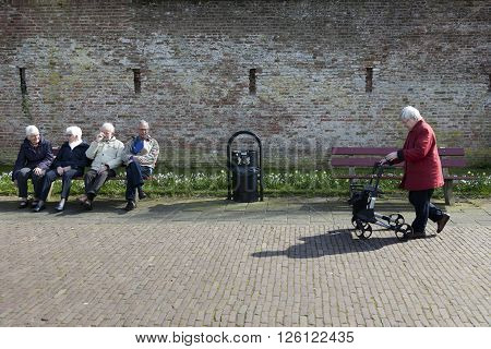 harderwijk, netherlands, 1 april 2016: four elderly people sit on bench in the old dutch town of harderwijk