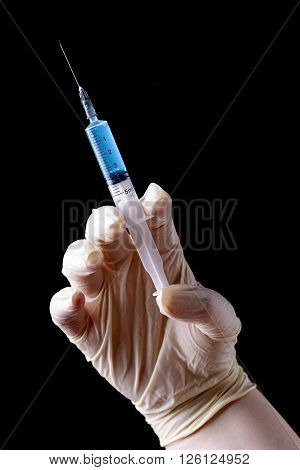 hand with surgical glove and syringe for injection on black background