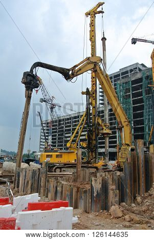 SELANGOR, MALAYSIA -MARCH 25, 2015: Sheet pile cofferdam driven machine at the construction site. The machine drove the sheet pile to the earth using vibrated hydraulic arm. Workers control.