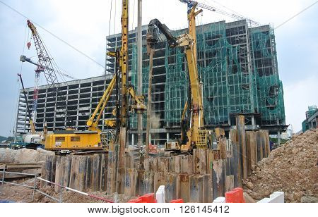 SELANGOR, MALAYSIA -MARCH 25, 2015: Sheet pile cofferdam driven machine at the construction site. The machine drove the sheet pile to the earth using vibrated hydraulic arm. Workers control.