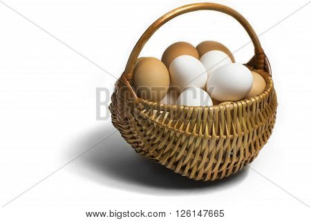 Light  brown wicker basket with colorful fresh eggs on a completely white background with a view angle of 45 degrees.
