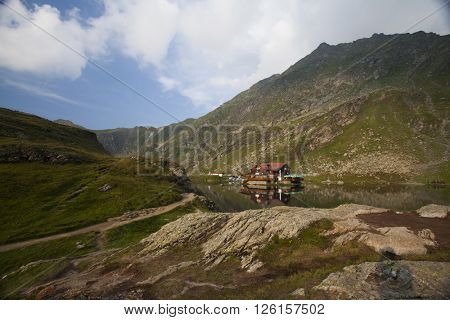 BALEA LAKE, ROMANIA - JULIY 22, 2015: Beautiful view of Balea Lake cottage on Fagaras Mountains, Carpathian, Romania. The image of the chalet is reflected in the lake.