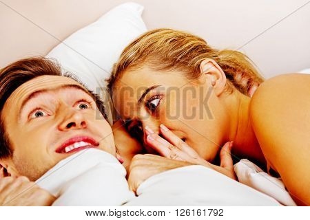 Woman whispering to her husband and he laughting