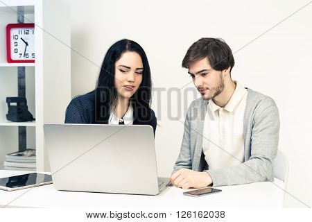Man and woomen working together. Two young people working together while sitting in minimalistic white athmosphere