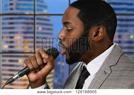 Afro singer with microphone. Singing male on skyscraper background. Recording studio in high building. New single from upcoming album.