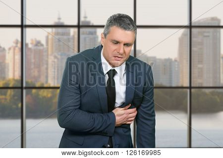 Mature male has heart pain. Ill businessman on city background. Ease the heartache. Chief needs medical attention.