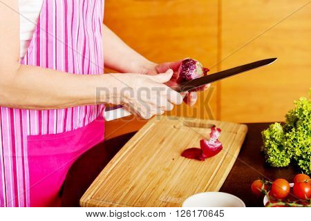 Woman cut red onion on cutting board