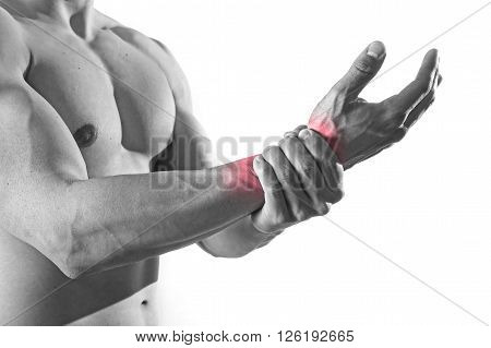 young man with strong muscle body holding with hand his damaged wrist suffering pain in sport injury and health care concept isolated on black and white with red spot sore area