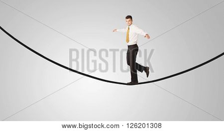 A confident smiling salesman balancing on black wire in clear grey empty space concept