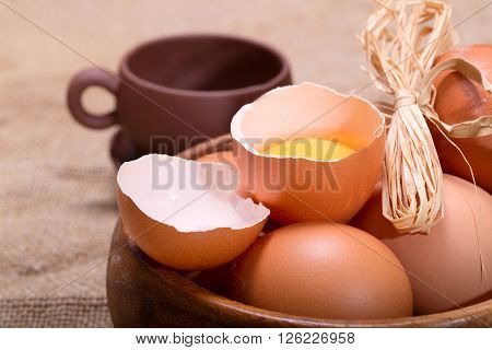 Eggs and clay cup on a sacking. One egg is broken rural style a close up