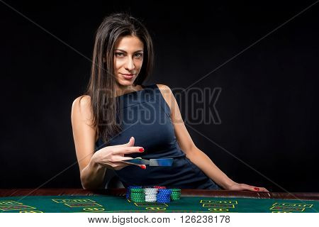 sexy woman with poker cards and chips. Female player in a beautiful black dress. throws a card.