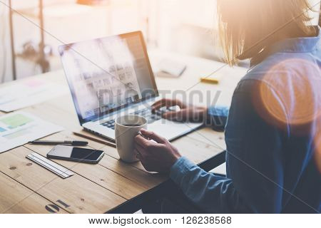 Working process modern office. Account manager working with new business project. Typing contemporary laptop, varios photo screen, on smartphone wood table. Horizontal. Film and flares effects