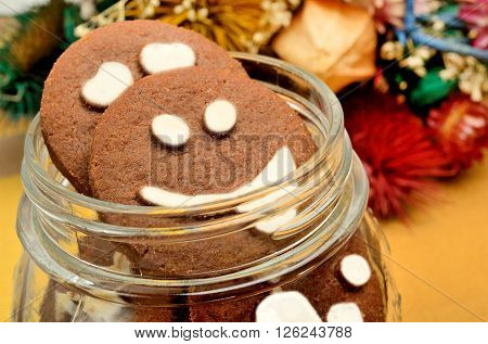 Jar with biscuits and dried flowers on table