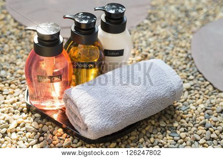 Bathroom amenity set on pebbles floor, bath gel, shampoo and conditioner