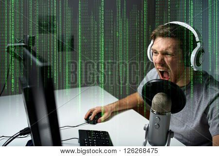 technology, gaming, entertainment, let's play and people concept - angry screaming young man in headset with pc computer playing game at home and streaming playthrough or walkthrough video
