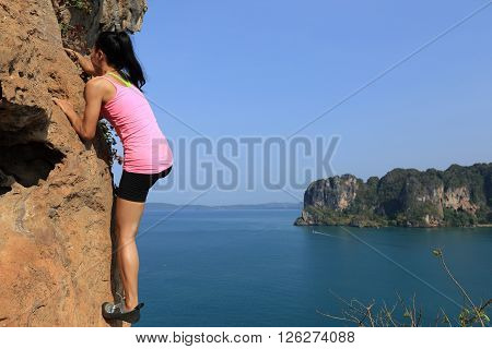 free solo woman rock climber climbing at seaside mountain rock wall
