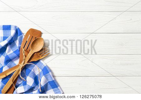 Wooden spoons and other cooking tools with blue napkins on the kitchen table.