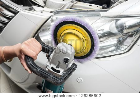 Car detailing series : Worker polishing white car headlights