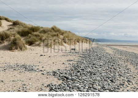 low down shot of beach with pebbles and grassy dunes in Ynyslas, Wales, UK