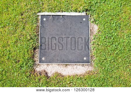 Metal Manhole Cover Drainage System In The Midst Of Cropped Grass