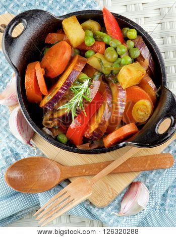 Delicious Homemade Colorful Vegetables Ragout with Eggplant Carrots Potatoes Leek Red Bell Pepper and Green Pea in Black Iron Stewpot with Wooden Spoon and Fork closeup on Blue Napkin
** Note: Soft Focus at 100%, best at smaller sizes