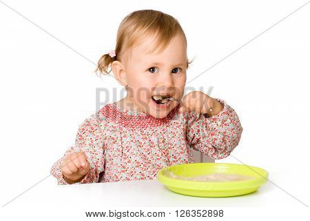 Hungry little child eating porrige, isolated over white