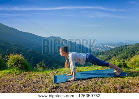 Woman doing Hatha yoga asana Kumbhakasana plank pose  outdoors in mountains