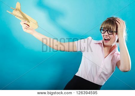 Fly fear metaphor aerophobia concept. Business woman holding airplane in hand vivid blue background