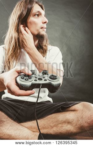 Addiction effects concept. Young unhappy depressed man with pad joystick playing games. Male addicted to console playstation videogames.
** Note: Shallow depth of field