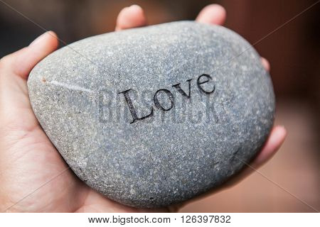 Hands holding pebble stones with the word love