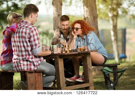 Boys and girls in nature disport playing chess